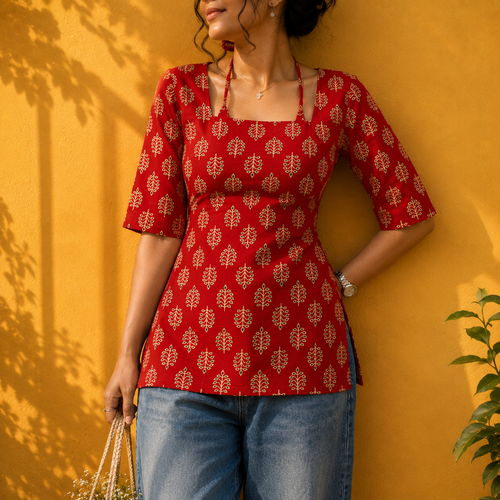 Woman wearing a red patterned top against a yellow wall